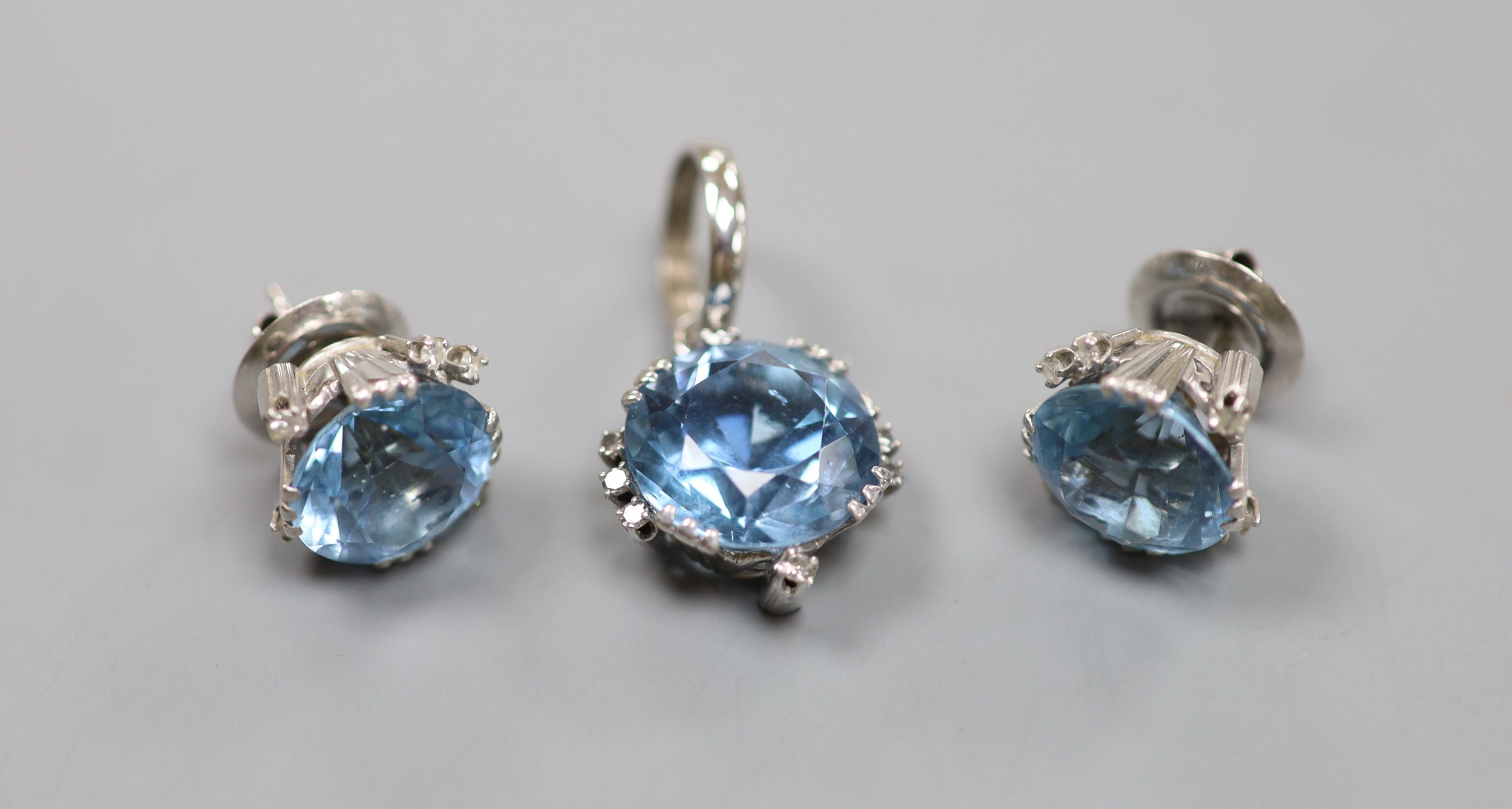 A modern pair of white metal, aquamarine and diamond set ear studs and a matching pendant